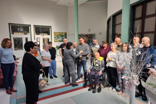 Mieszkańcy stoją na holu domu podczas kiedy Pani Wójt składa im życzenia.