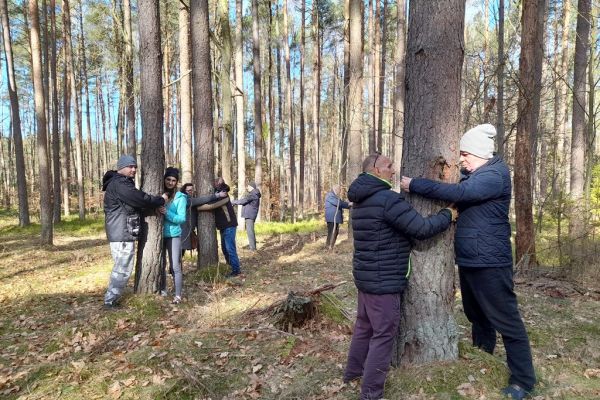 Mieszkańcy parami obejmuja drzewa.