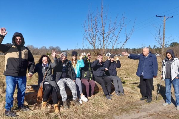 Mieszkańcy na dworze siedzą na kłodzie drewna.