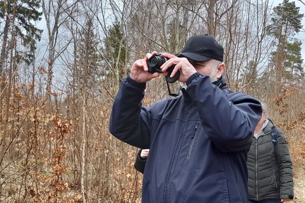 Mieszkaniec trzyma aparat i fotografuje przyrodę.