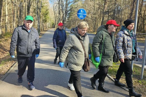 Mieszkańcy idą po lesie z workami do sprzątania.