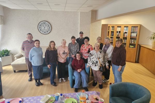 Grupowe zdjęcie mieszkańców w kawiarence zaproszonych na urodziny.