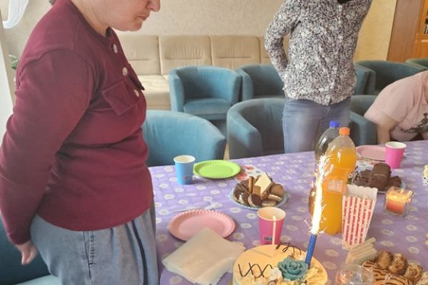 Jubilatka stoi przy torcie postawionym na stole.