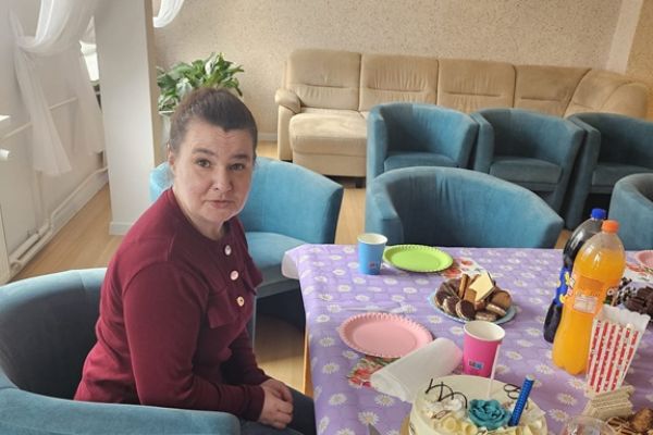 Jubilatka siedzi przy stole z ustawionym tortem.