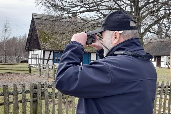 Mieszkaniec fotografuje aparatem zagrodę w Klukach.