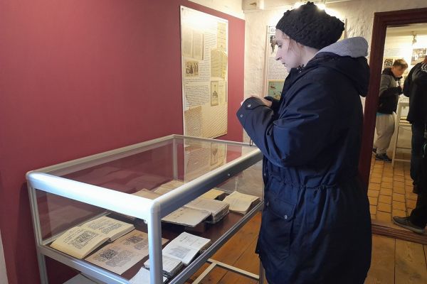 Mieszkanka fotografuje książki w gablocie w zagrodzie w Klukach.