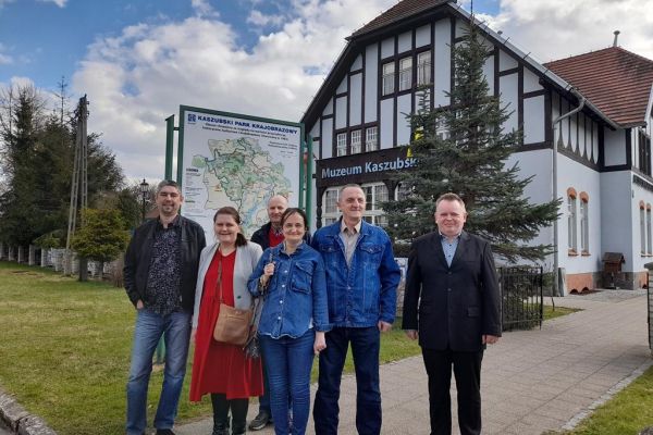 Grupa mieszkańców stoi przed budynkiem Muzeum w Kartuzach.