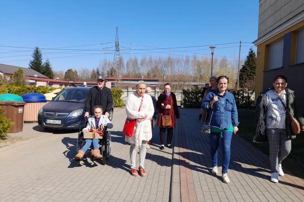 Mieszkańcy idą na teren szkoły oglądać występ dzieci.