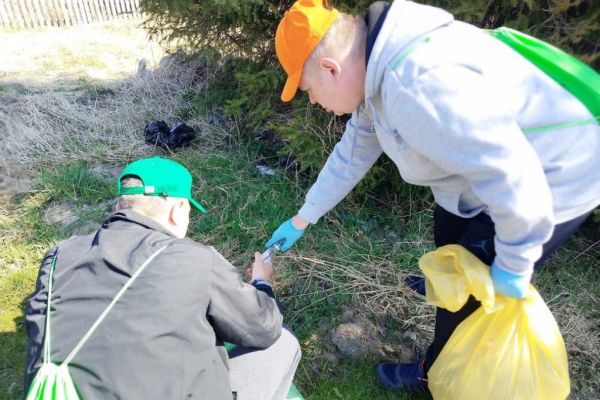 Mieszkańcy podnoszą śmieci i wrzucają do worka.