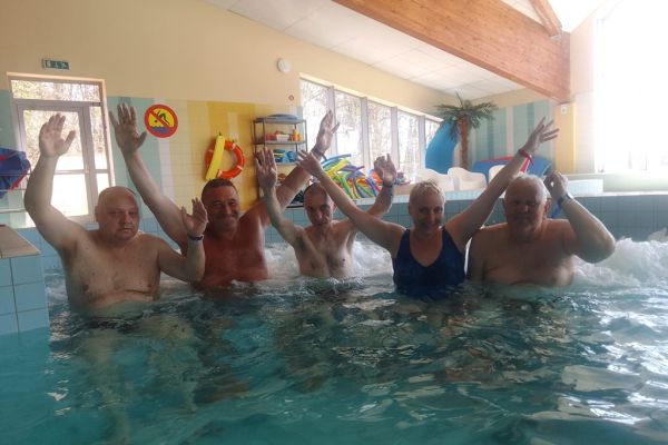 Grupowe zdjęcie pięciu mieszkańców z podniesionymi rękoma w wodzie.