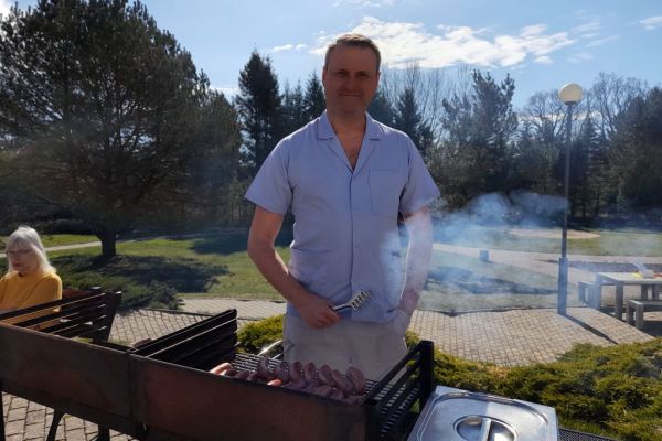 Opiekun stoi przy grillu.