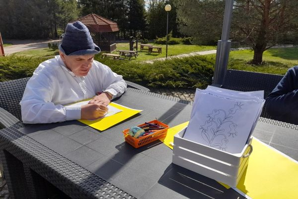 Mieszkańcy korzystają z grilla na tarasie, rysuja kredkami, tańczą,  grają w kręgle , częstują się kiełbaską.