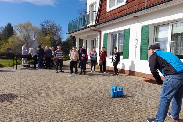 Mieszkańcy korzystają z grilla na tarasuie,tańczą,  grają w kręgle , częstują się kiełbaska