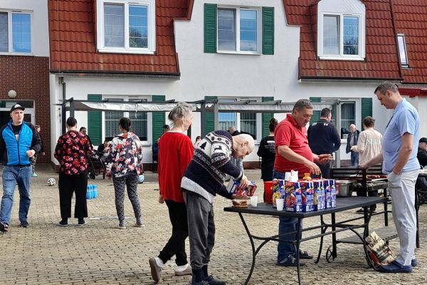 Mieszkańcy korzystają z grilla na tarasuie,tańczą,  grają w kręgle , częstują się kiełbaską.