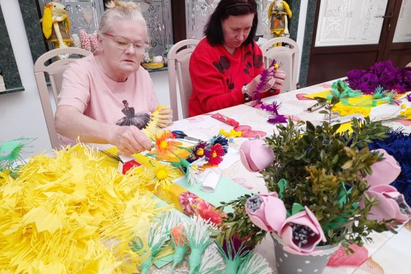 Mieszkańcy wykonują ręcznie kwiaty z pociętej bibuły.