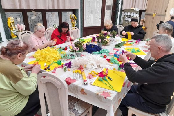 Mieszkańcy wykonują ręcznie kwiaty z pociętej bibuły.
