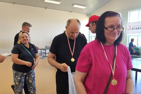 Mieszkańcy na hali sportowej odbieraja nagrody.