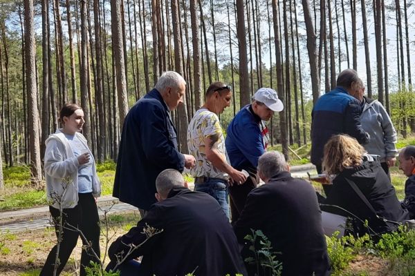 Mieszkańcy siedzą i stoją w lesie.