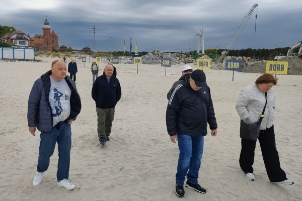 Mieszkańcy idą plażą.