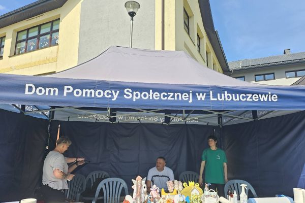 Namiot DPS a w nim pracownicy z wystawą prac mieszkańców.