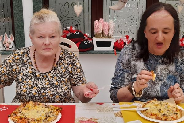 Mieszkanki jedzą pizze.