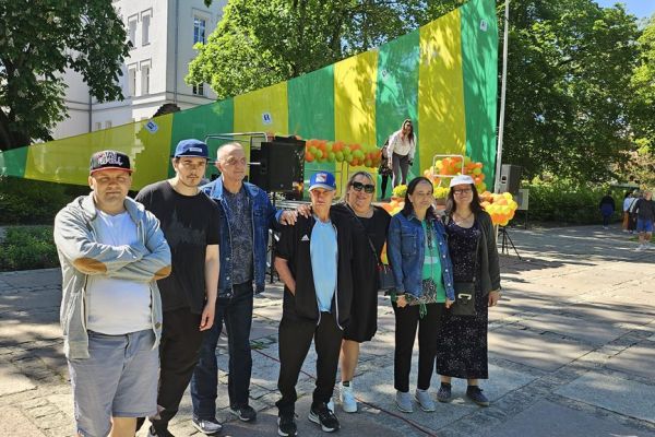 Grupa mieszkańców stoi podczas pikniku z okazji dnia godności osób z niepełnosprawnościami.