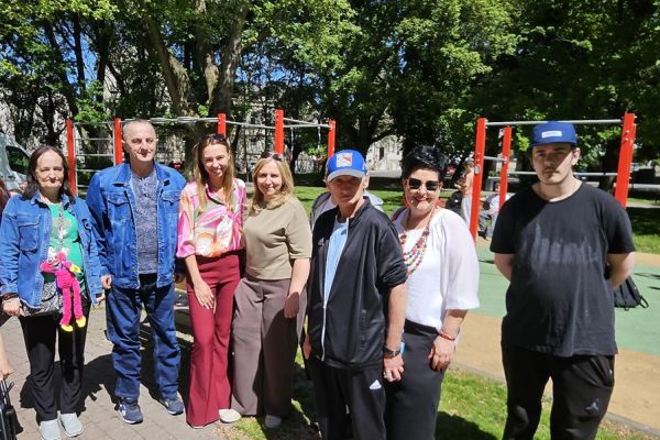Grupa mieszkańców stoi podczas pikniku z okazji dnia godności osób z niepełnosprawnościami.