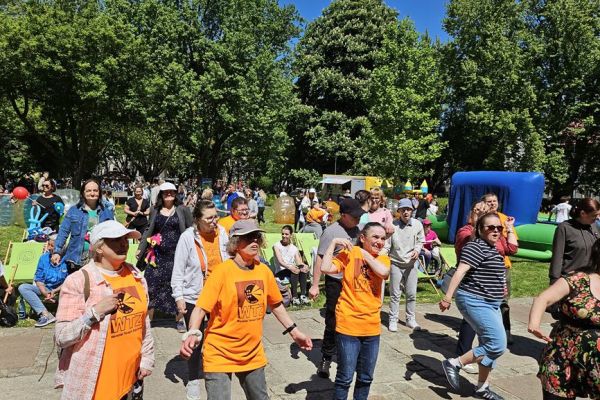 Grupa mieszkańców stoi podczas pikniku z okazji dnia godności osób z niepełnosprawnościami.