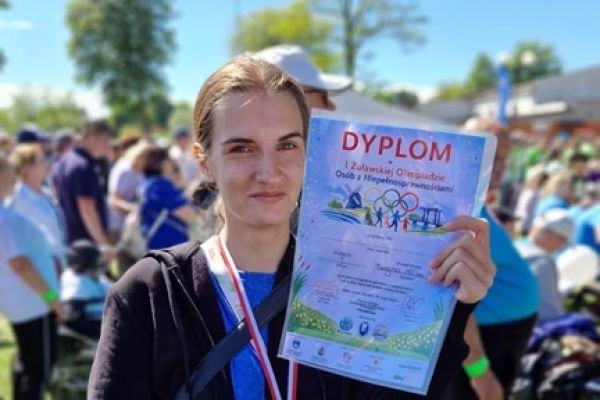 Mieszkanka trzyma dyplom i nagrodę.