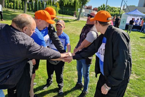 Grupa mieszkańców składają ręce do okrzyku.