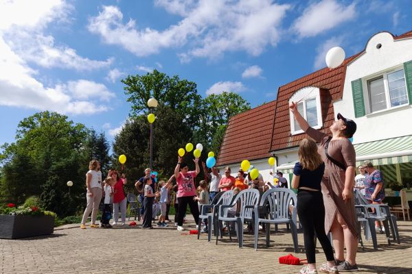 Uczestnicy pikniku puszczają balony do nieba.