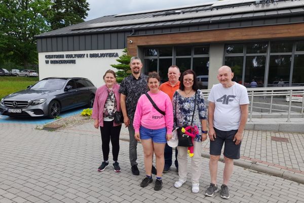 Grupa mieszkańców przed budynkiem biblioteki.