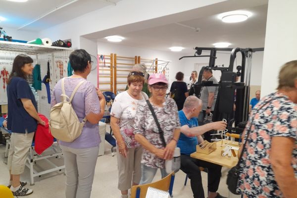 Goście w sali rehabilitacji ruchowej wśród ćwiczących mieszkańców.