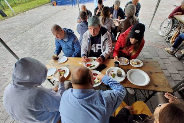 Mieszkańcy przy poczęstunku na pikniku.