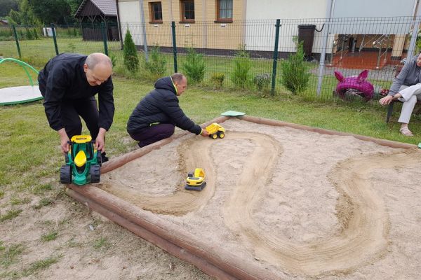 Mieszkańcy bawia się samochodami w piaskownicy.