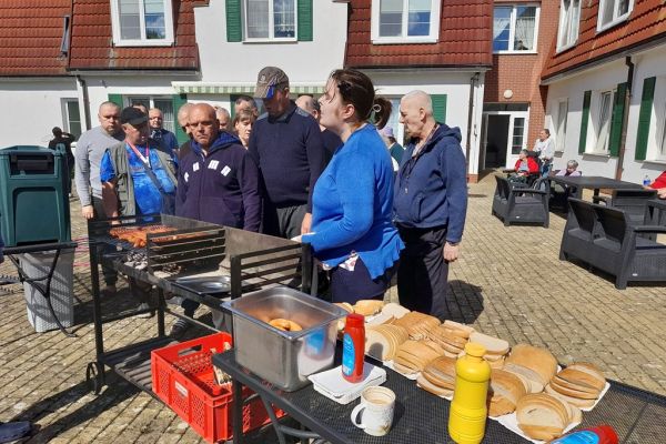 Mieszkańcy stoją przy grillu.