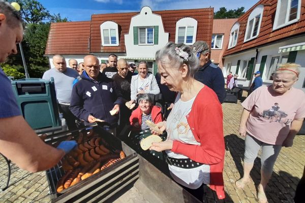Mieszkańcy stoją przy grillu.