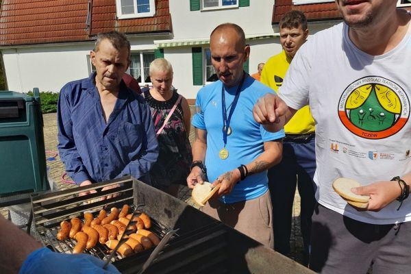 Mieszkańcy stoją przy grillu.