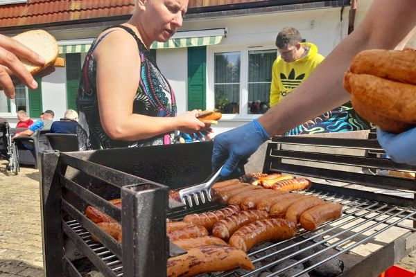 Mieszkańcy stoją przy grillu.