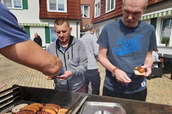 Mieszkańcy stoją przy grillu.