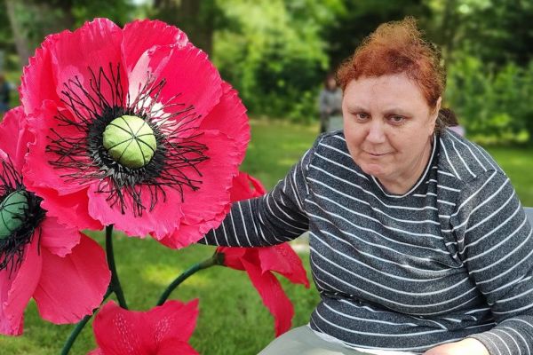 Mieszkanka na ławce z kwiatem z bibuły.