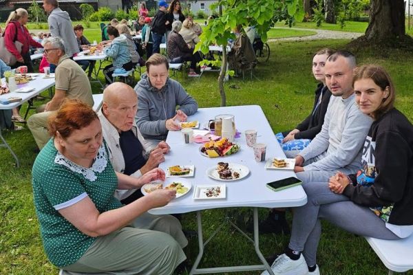 Grupa mieszkańców przy stoliku na poczęstunku.
