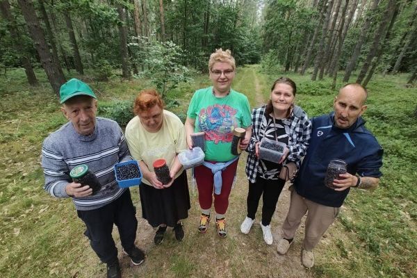 Mieszkańcy pokazuja uzbierane jagody.