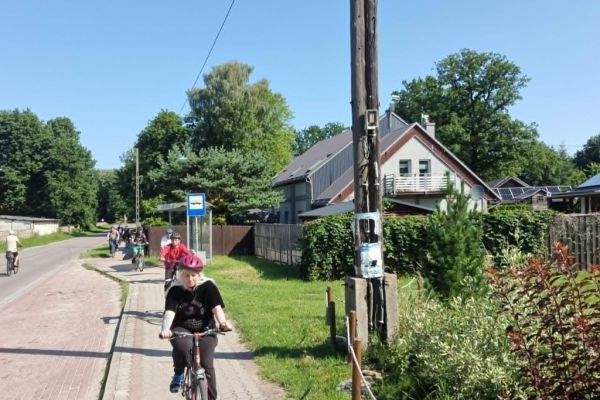 Mieszkańcy jadą na rowerach po wiosce.