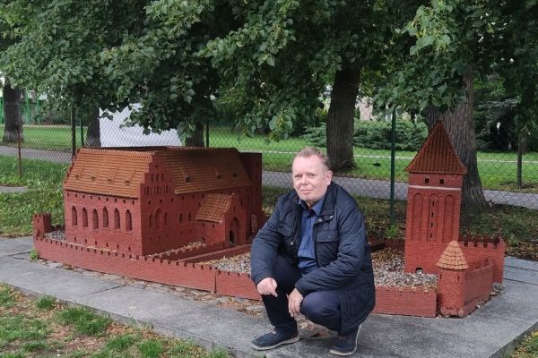 Mieszkaniec przy minaturze zamku.