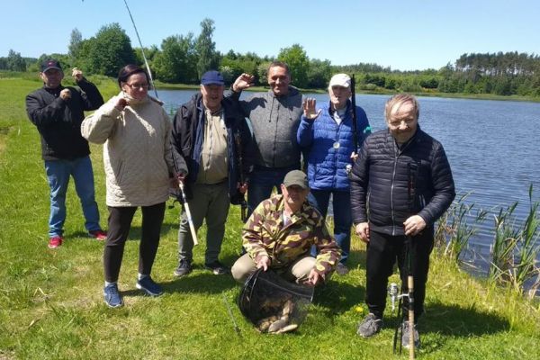 Grupowe zdjęcia mieszkańców przy stawie po złowieniu ryb.