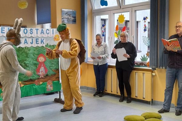 Mieszkańcy przedstawiaja bajkę w strojach zająca i żówia.