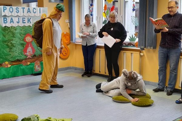 Mieszkańcy przedstawiaja bajkę w strojach zająca i żówia.