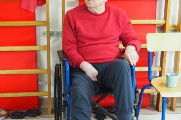 Mieszkańiec ćwiczy na sprzęcie do ćwiczeń w sali rehabilitacyjnej.