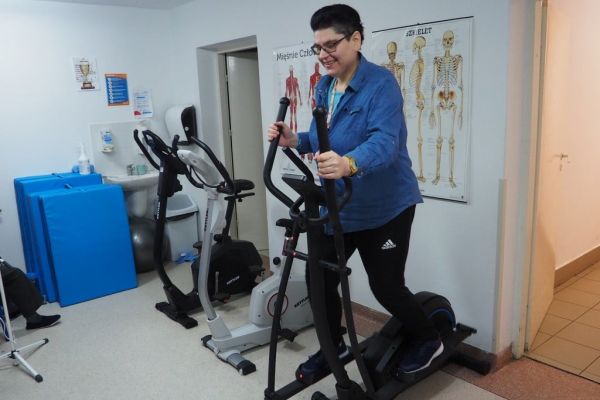 Mieszkanka ćwiczy na sprzęcie do ćwiczeń w sali rehabilitacyjnej.